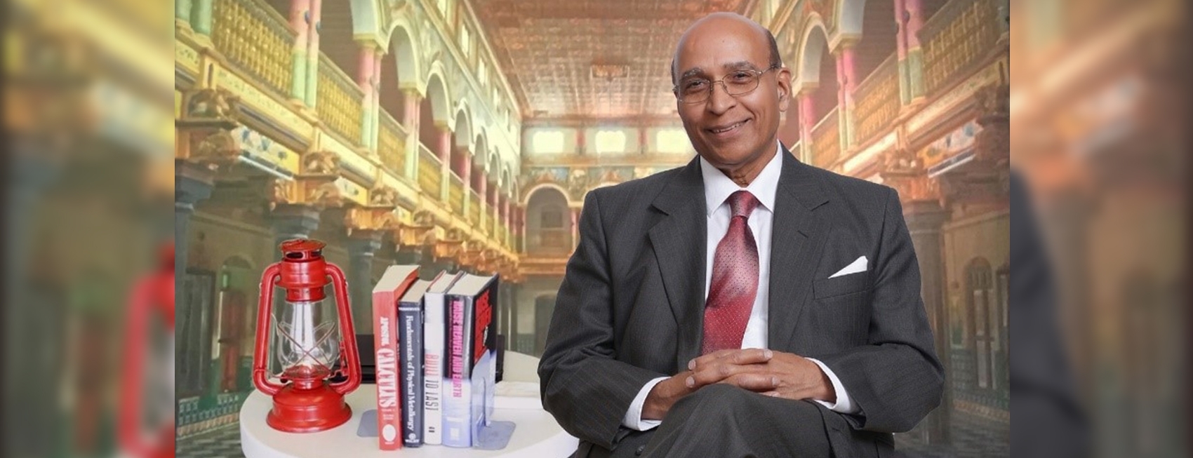 Paresh Modi seated in a fancy library atrium with several books and a latern next to him